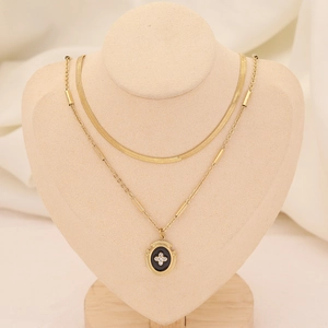 Détail du collier à plusieurs rangs doré et pendentif ovale noir avec croix