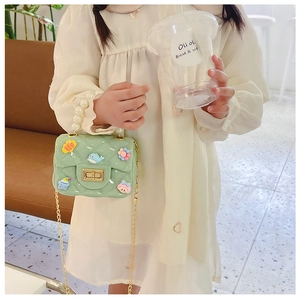 Detail of girls mint green crossbody bag with pearl handle and cartoon charms