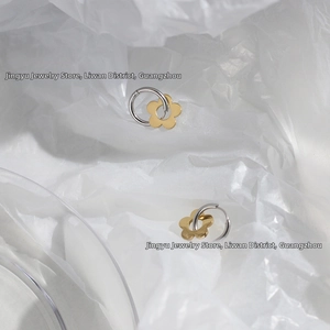 Detail of minimalist daisy flower charm earrings in mixed silver and gold tones