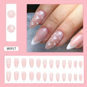 Detail view of W957 almond fake nails featuring nude pink finish with white hearts and silver glitter