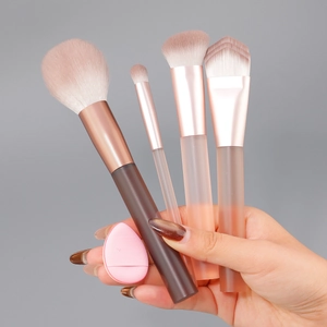 Hand holding 4pcs makeup brush set with foundation brush and sponge in gift box