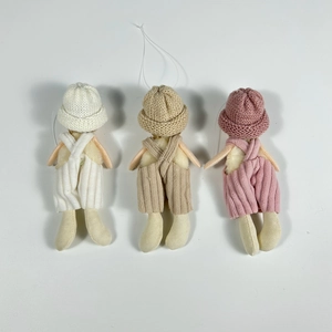 Detail of three knitted doll ornaments in white, beige, and pink for Christmas trees