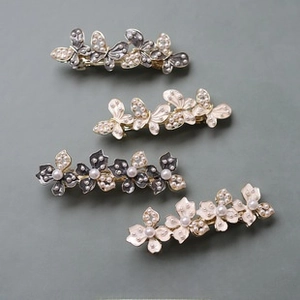 Detail of 4-piece hair clip set with white faux pearls and silver floral butterfly designs