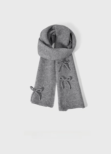 Detail of grey knitted scarf showing soft wool blend texture and decorative bow accents