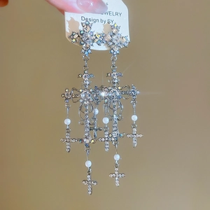 Macro view of crystal cross earrings with long pearl tassels and shimmering rhinestones