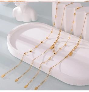 Détail de quatre bracelets de cheville en acier titane doré avec perles carrées et breloques