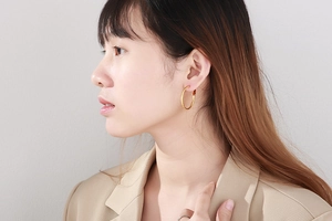 Close-up of oversized golden hoop earrings with textured finish worn by a model