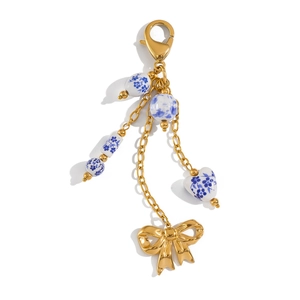 Détail macro du porte-clés doré avec perles en céramique florales bleues et nœud
