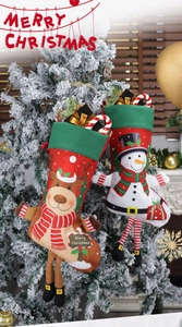 Detail of 3D reindeer and snowman Christmas stockings hanging on a snowy holiday tree