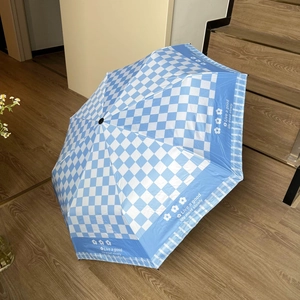 Detail of blue checkerboard umbrella with white daisy patterns and stylish text