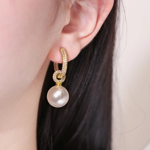 Élégantes créoles dorées avec perles blanches et zircons scintillants portées par le mannequin