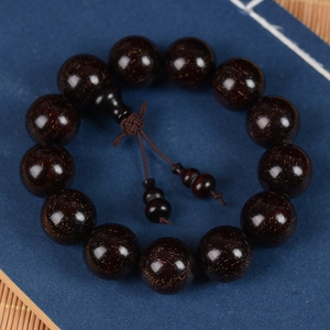 Blood Sandalwood Buddhist beads bracelet with golden specks on dark wood texture