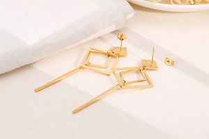 Detail of geometric rhombus gold earrings with vertical drop pendant and metallic finish