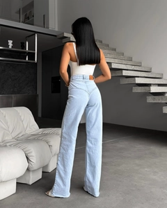 Détail du jean taille haute bleu clair montrant l'effet galbant et les ourlets effilochés