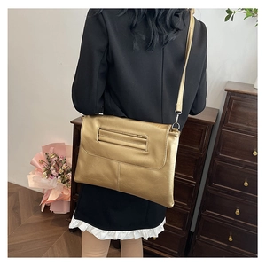 Detail of a metallic gold envelope crossbody bag with fine PU leather texture and strap