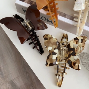 Detail of tortoise shell and dark brown acetate butterfly hair claw clips on books