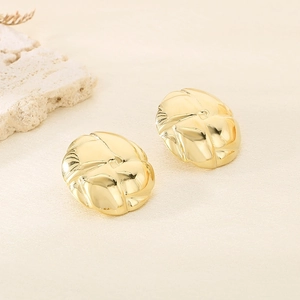 Detailed macro view of golden metal hoop earrings with irregular wave texture