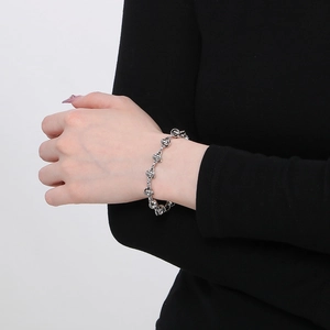 Gros plan d'un bracelet à boules argentées entrelacées au poignet d'un mannequin