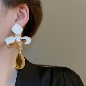 Close-up of flower stud earring with amber teardrop tassel on a model silhouette