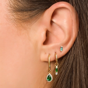 Golden earring set with green pear-shaped stones and white crystals on ear model