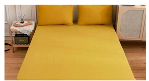 Detail of ginger yellow fitted sheet and matching pillowcases set in a modern bedroom