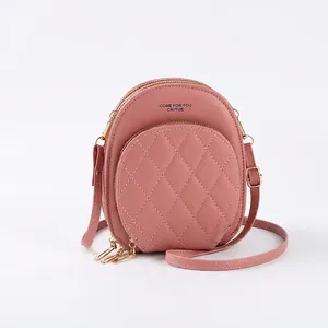 Detail of pink quilted synthetic leather round crossbody bag with gold metal zippers