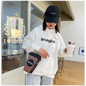 Street style view of a creative coffee cup shaped crossbody bag with gold chain strap