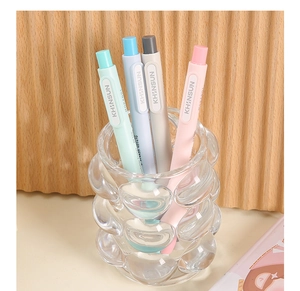Close-up of Morandi colored retractable pen-style erasers in a glass pen holder