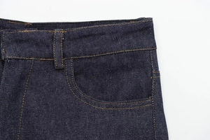 Detail of dark blue denim jeans waist with yellow contrast stitching and belt loops