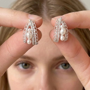 Detail shot of boho-style hollow drop earrings featuring three graduated pearls in silver