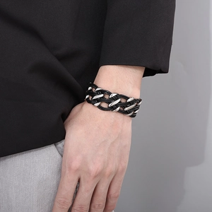 Detail of hand wearing a double-layered black woven leather bracelet with steel accents
