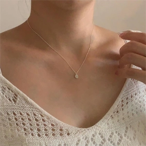 Close-up of minimalist silver water drop pendant necklace on a model's collarbone