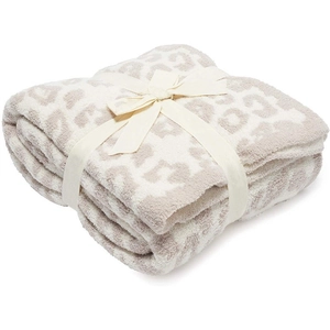 Folded light brown leopard print fleece blanket tied with a cream ribbon gift bow