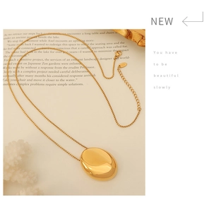 Close-up of a gold oval pendant necklace resting on a vintage book page with artistic text