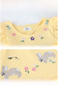 Detailed close-up of colorful floral embroidery and cute bee patch on yellow cotton dress