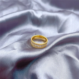 Detail shot of golden belt-style titanium ring with micro-inlays on grey silk fabric