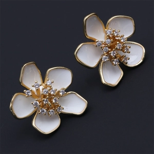 Detail of flower earrings with gold base, white enamel petals and sparkling rhinestones