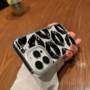 Close-up of clear iPhone case with black kiss mark pattern held over wooden desk