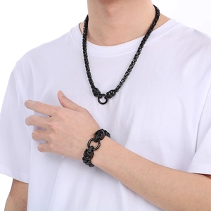 Detail of punk black skull necklace and bracelet set on male model in white t-shirt