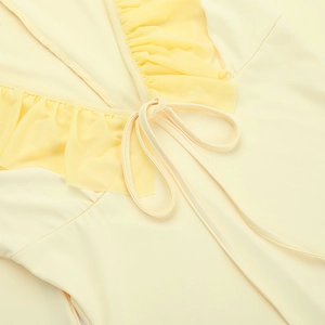 Close-up of a deep V-neckline with delicate mesh ruffles and drawstring in pale yellow