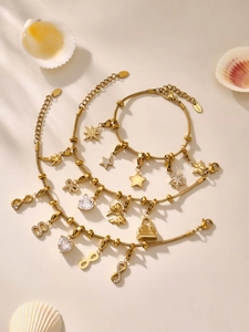 Dettaglio di bracciali in acciaio inossidabile dorato con stelle, cuori e ciondoli chic