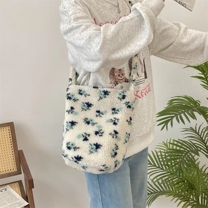 Close-up of fluffy floral tote bag with blue patterns worn by model for winter style