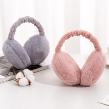 Detail view of plush cat paw ear warmers in pink and gray on a cozy desktop display