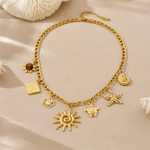 Golden stainless steel ocean charms necklace with tiger eye stone on sandy beach texture