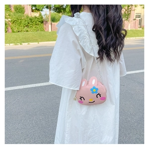 Pink cartoon rabbit crossbody bag for girls shown on white dress in outdoor setting