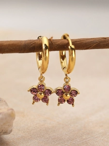 Detail of flower-shaped earrings with purple crystals on a natural branch display