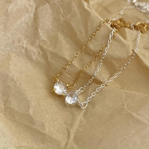 Detail of minimalist 925 silver four-prong cubic zirconia necklaces in gold and silver colors