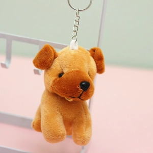Detailed view of a brown plush dog keychain with a golden bell and silver metal clasp