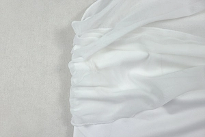 Detailansicht aus weißem, transparentem Netzstoff mit eleganten Raffungen und Falten