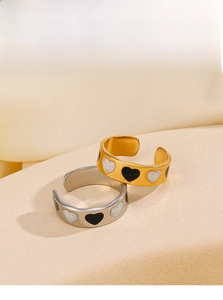 Close-up of adjustable gold and silver heart rings with black and white enamel details